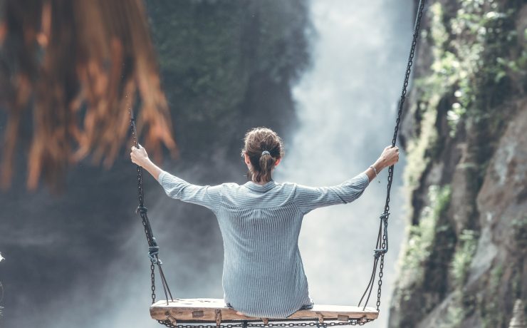Woman Riding Big Swing in Front of Waterfalls